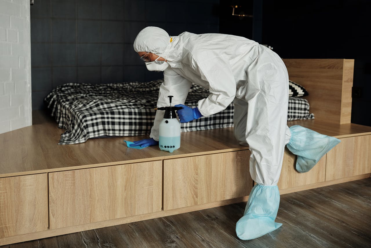 Worker in protective gear sanitizing a bedroom during the COVID-19 pandemic.